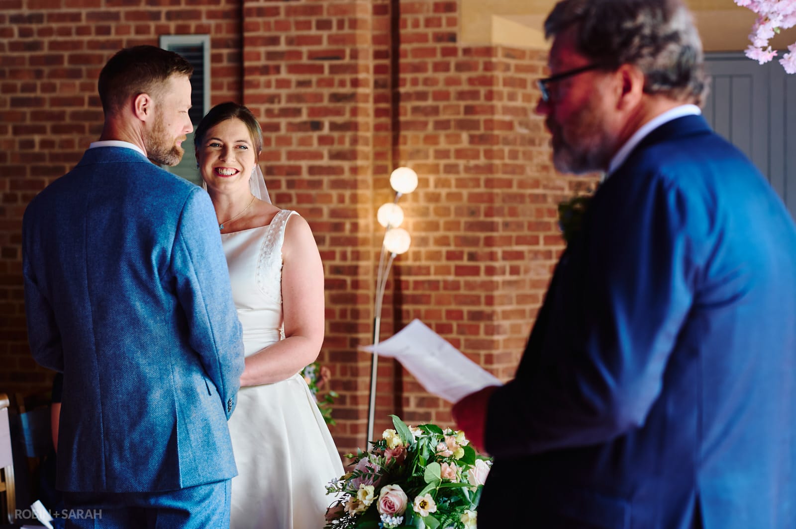Bride listens to guest delivering reading during wedding ceremony.