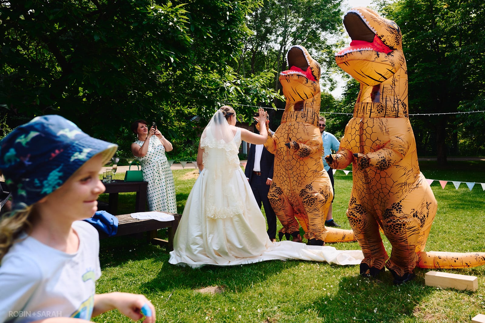 Bride high-fives wedding guests dressed in t-rex costumes