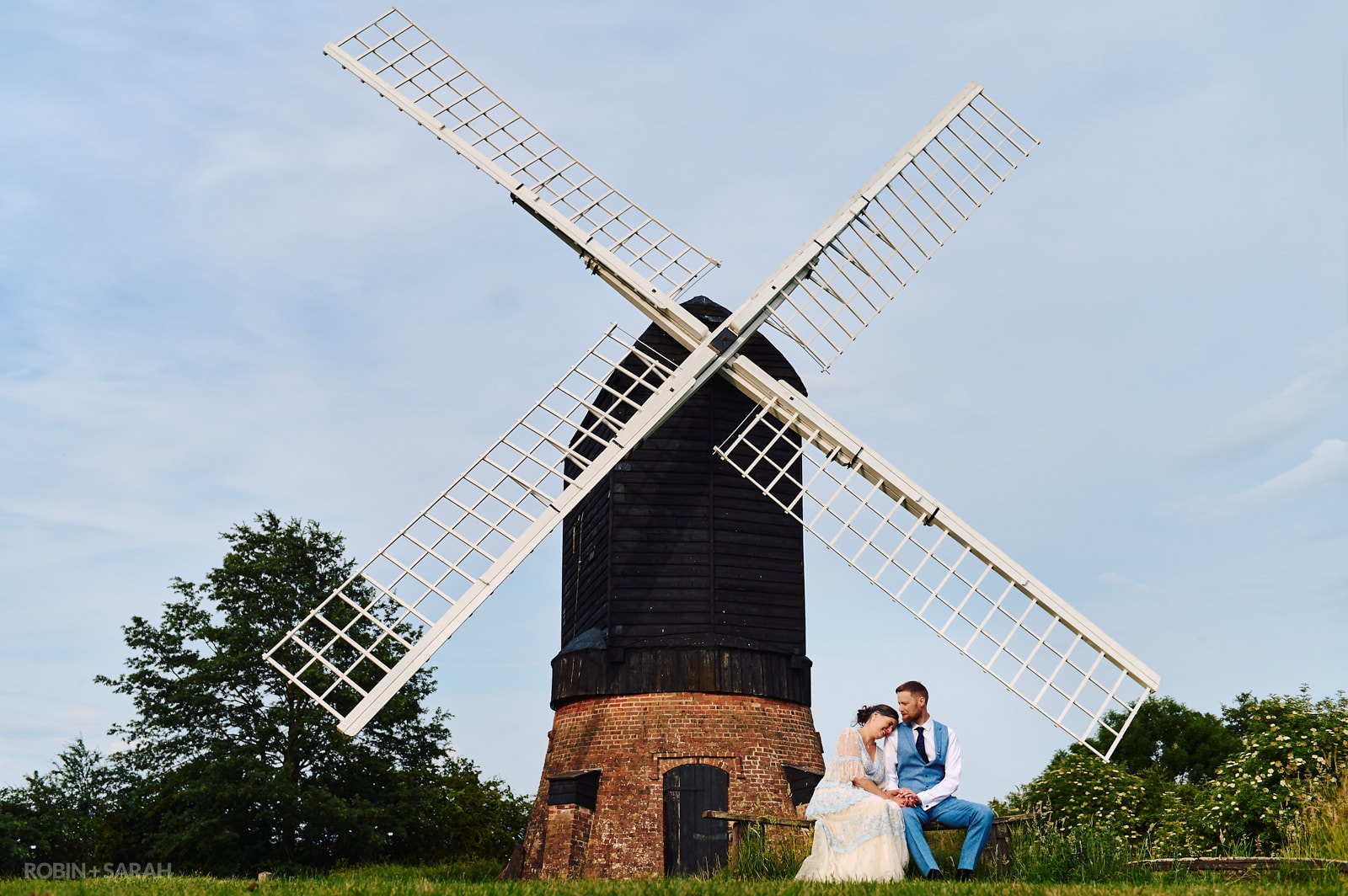 Bride and groom sitting net to windmill at Avoncroft Museum on their wedding day