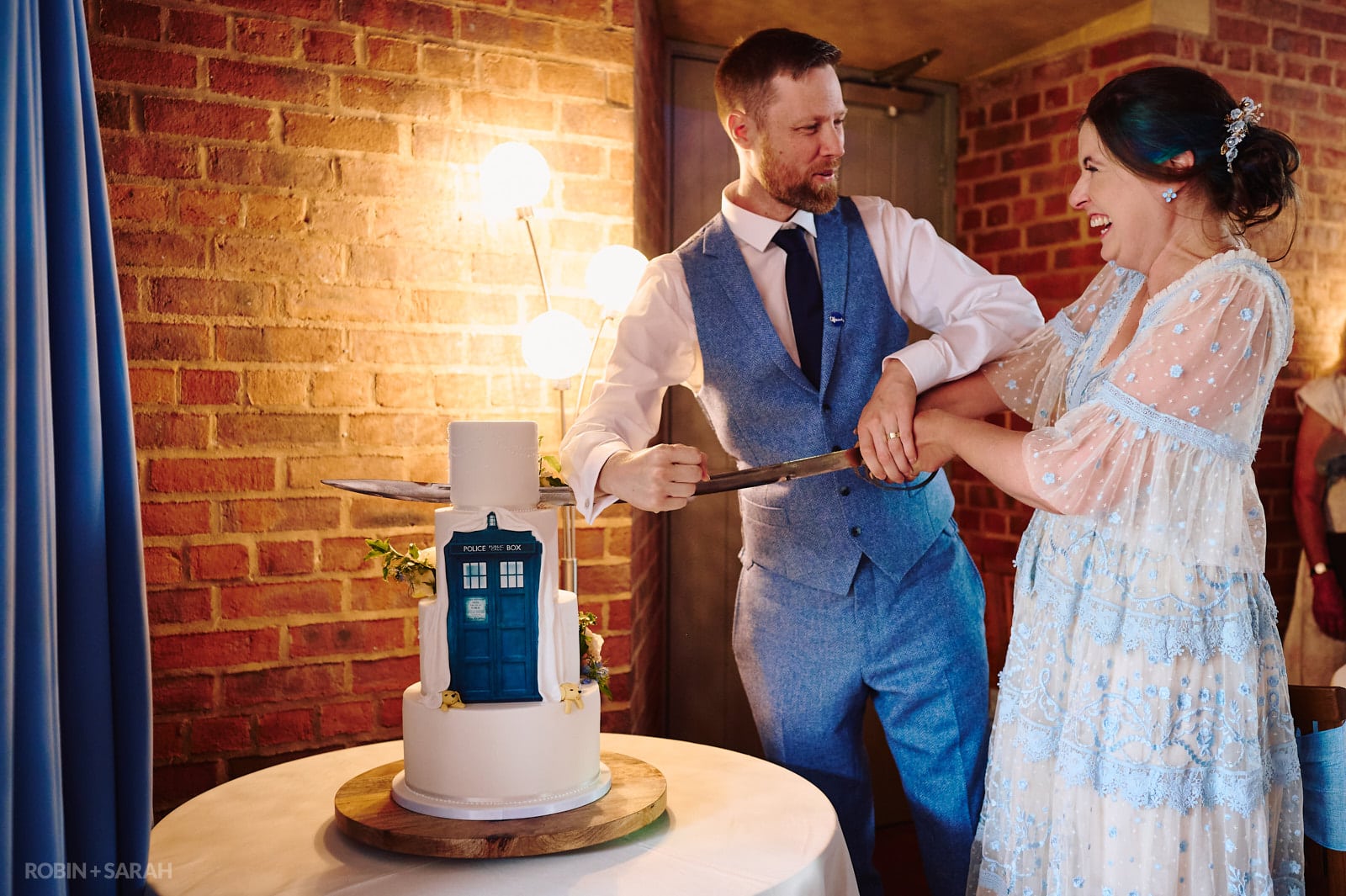 Bride and groom cut wedding cake with curved sword