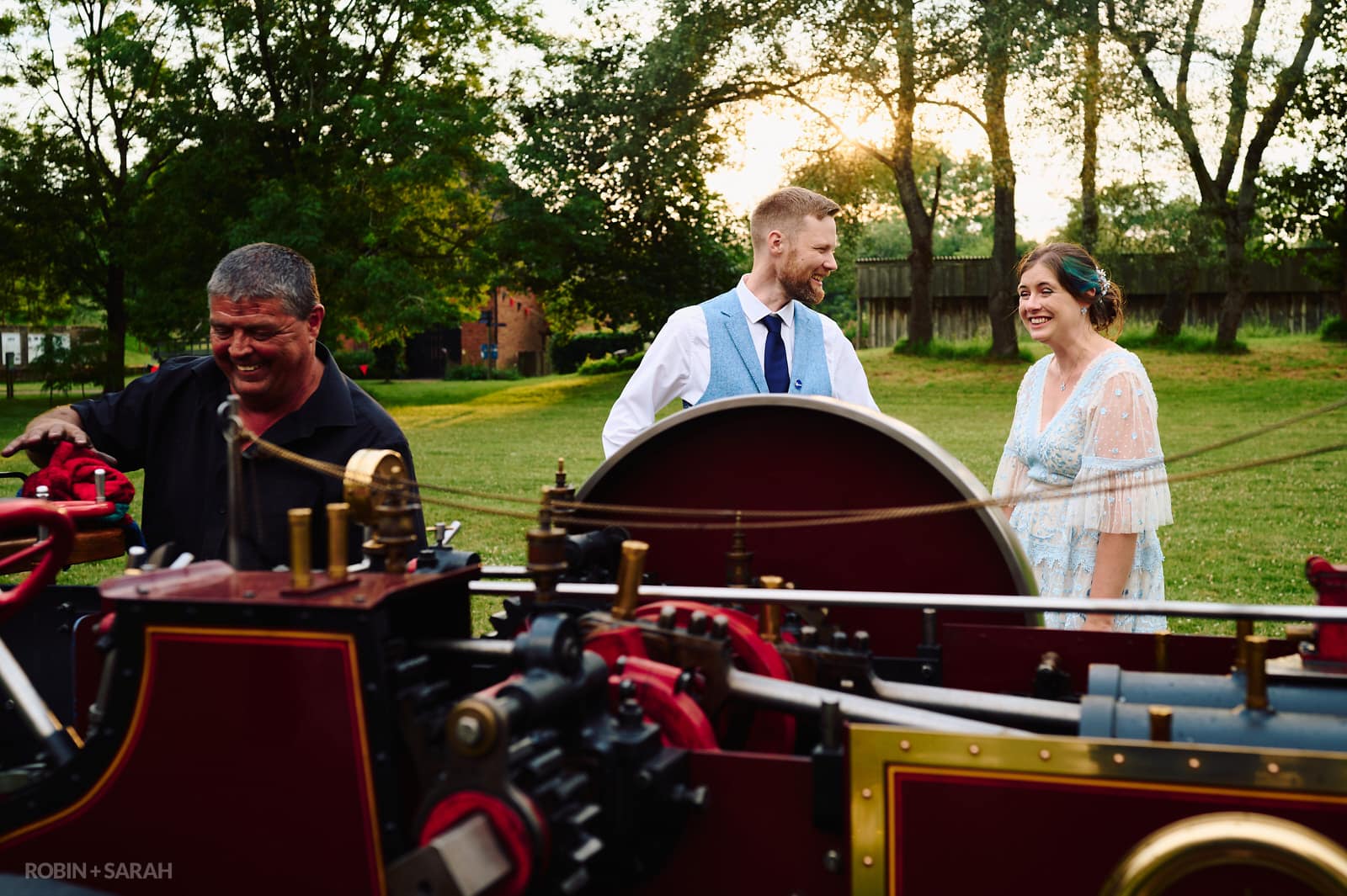 Bride and groom laughing with driver of traction engine