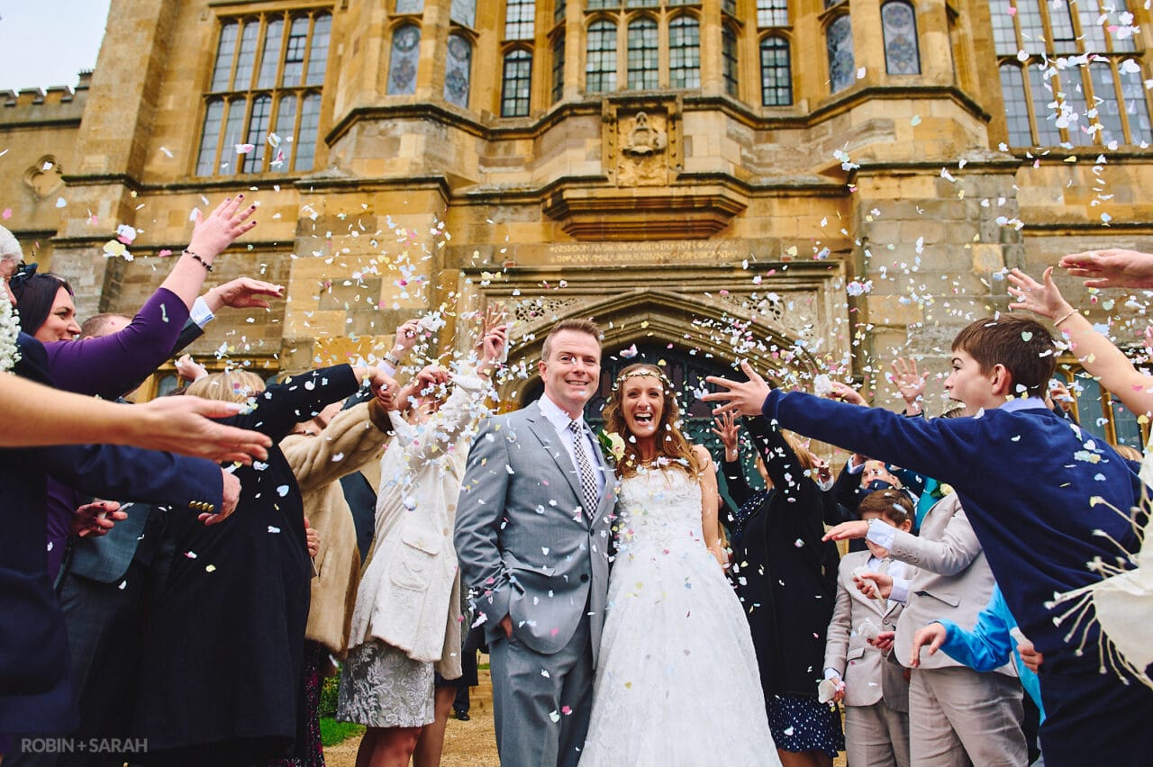 Bride and groom have confetti thrown over them in front of Coughton Court