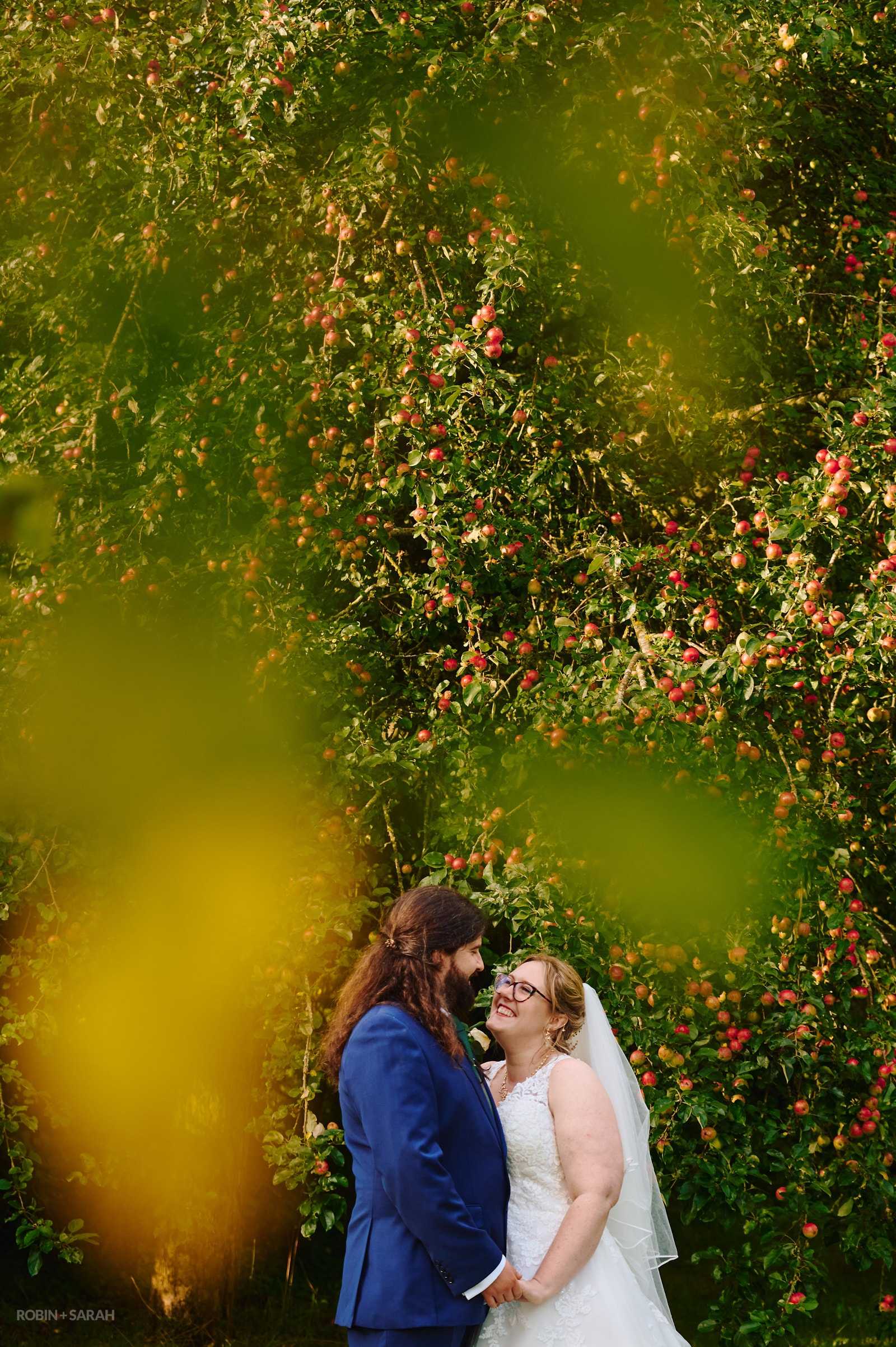 Bride and groom surrounded by apple orchard