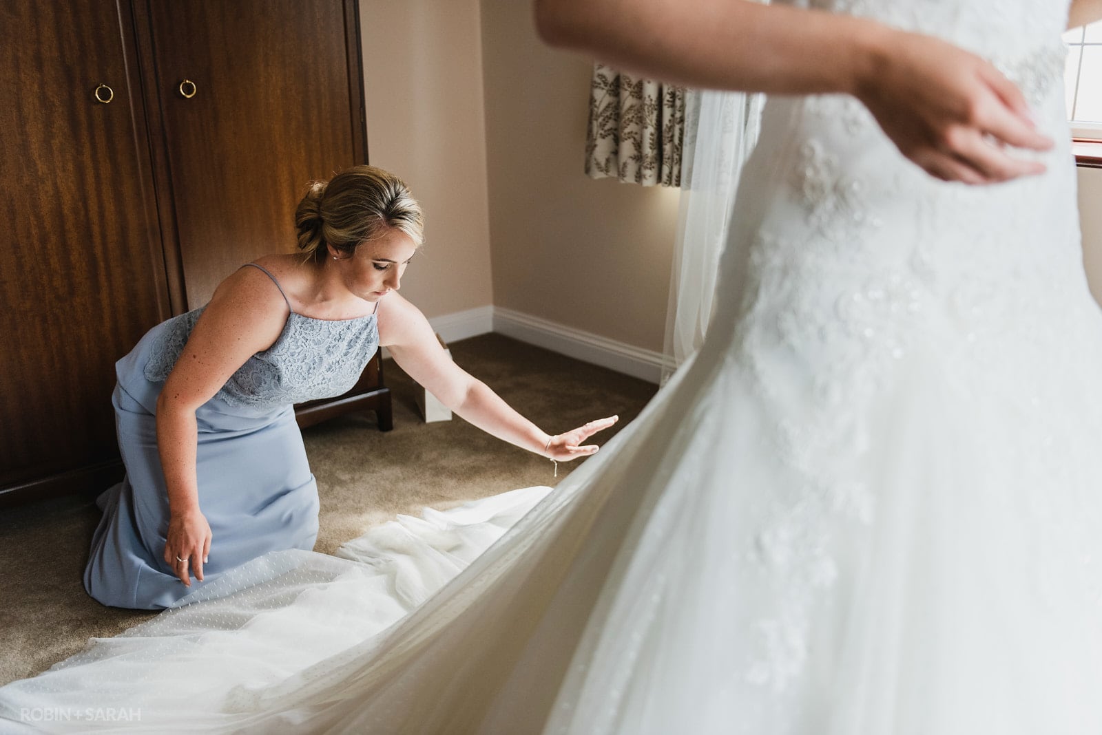 Bridesmaid spreads wedding dress out