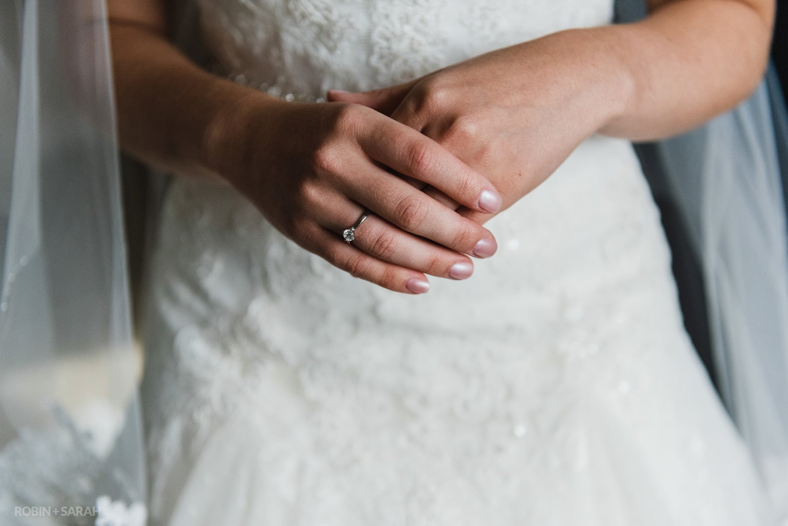 Bride's hands as she has wedding dress fastened