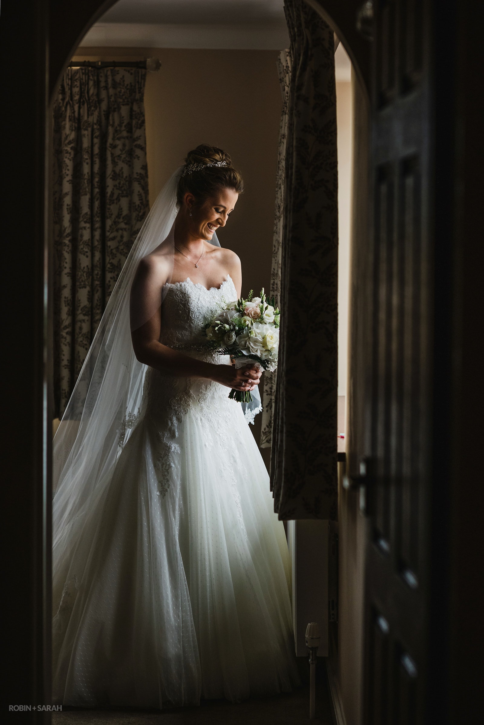 Portrait of bride wearing white wedding dress with cathedral veil standing in doorway