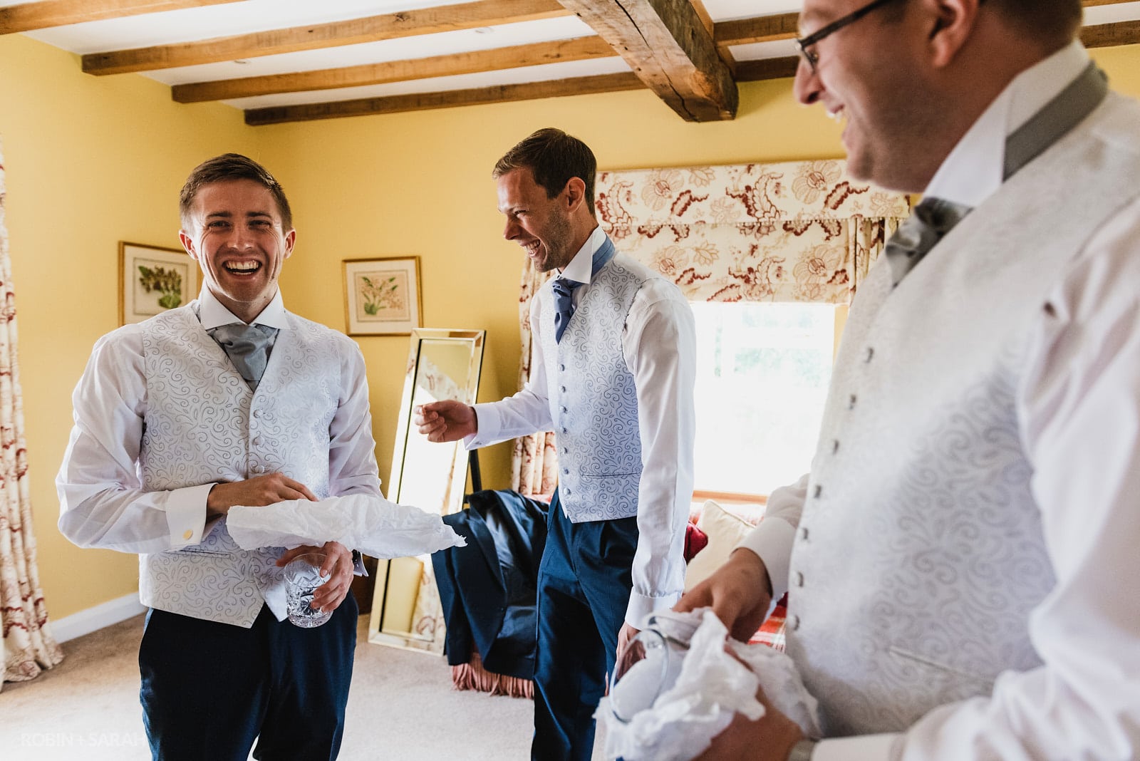 Groom and groomsmen laugh as they prepare for wedding