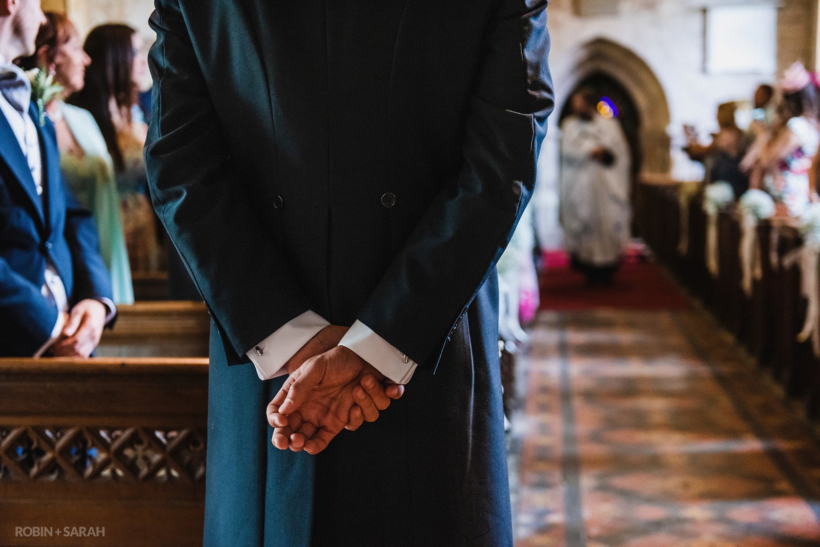 Groom's hands behind his back as he waits in church