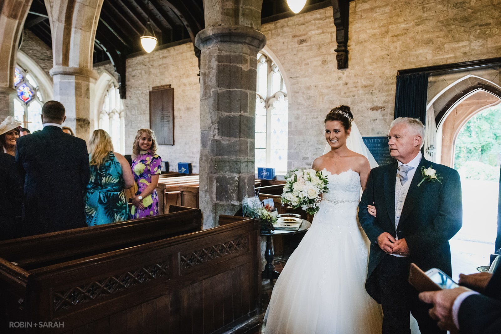 Bride and dad enter church wedding ceremony as guests turn around to look