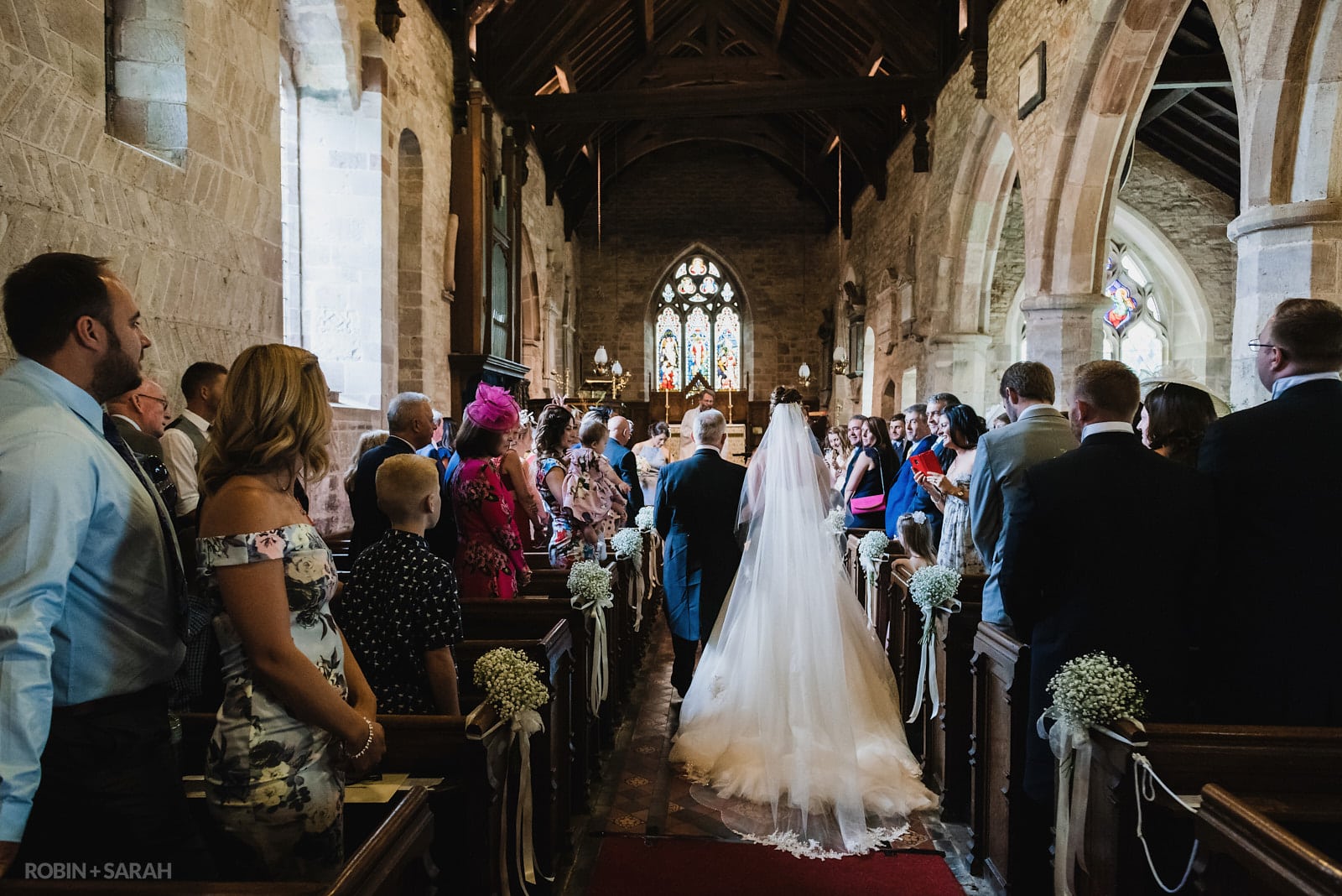 Bride and dad walk up aisle of St Peter's Church Diddlebury at start of wedding ceremony