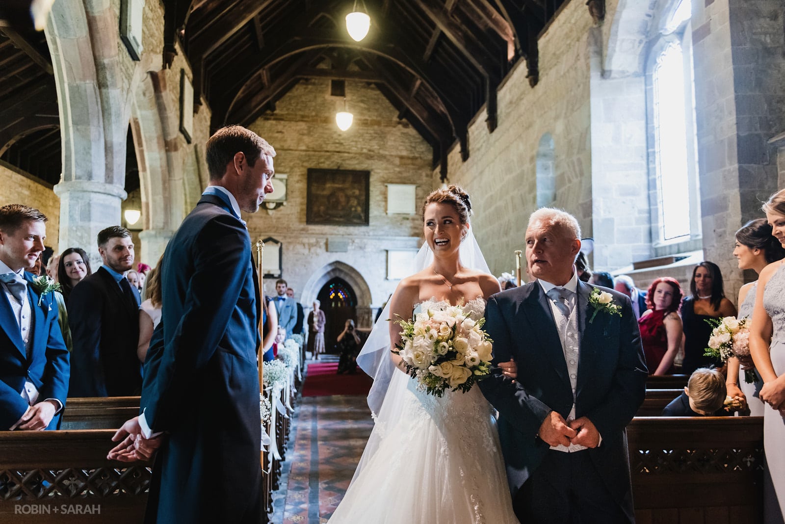 Bride laughs as she sees groom at start of church wedding ceremony