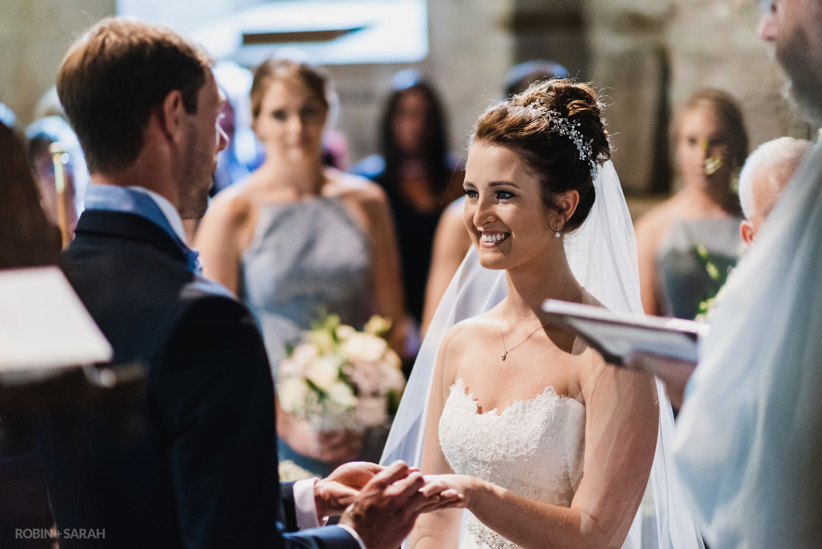Bride smiles during wedding ceremony in St Peter's Church Diddlebury