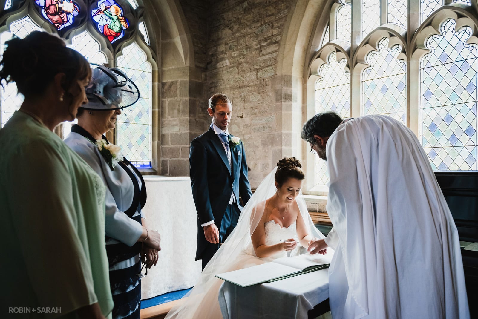Bride and groom sign marriage register in St Peter's Church Diddlebury