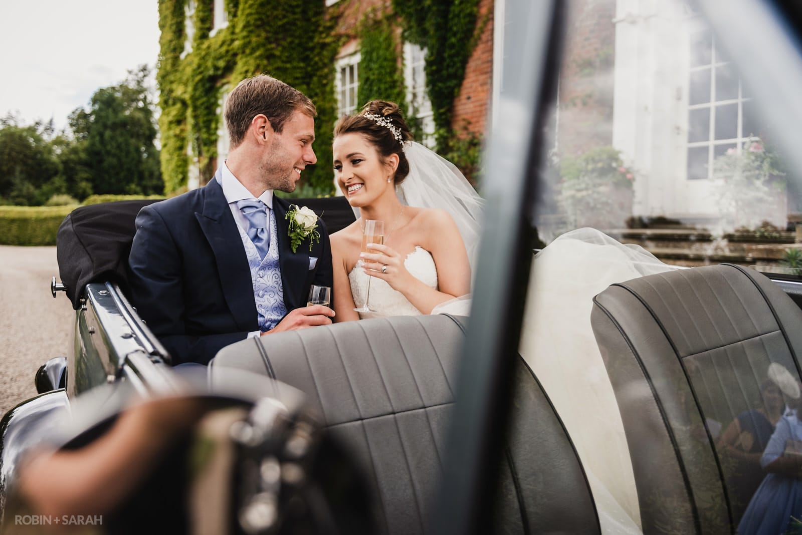 Bride and groom in open-top car at Delbury Hall