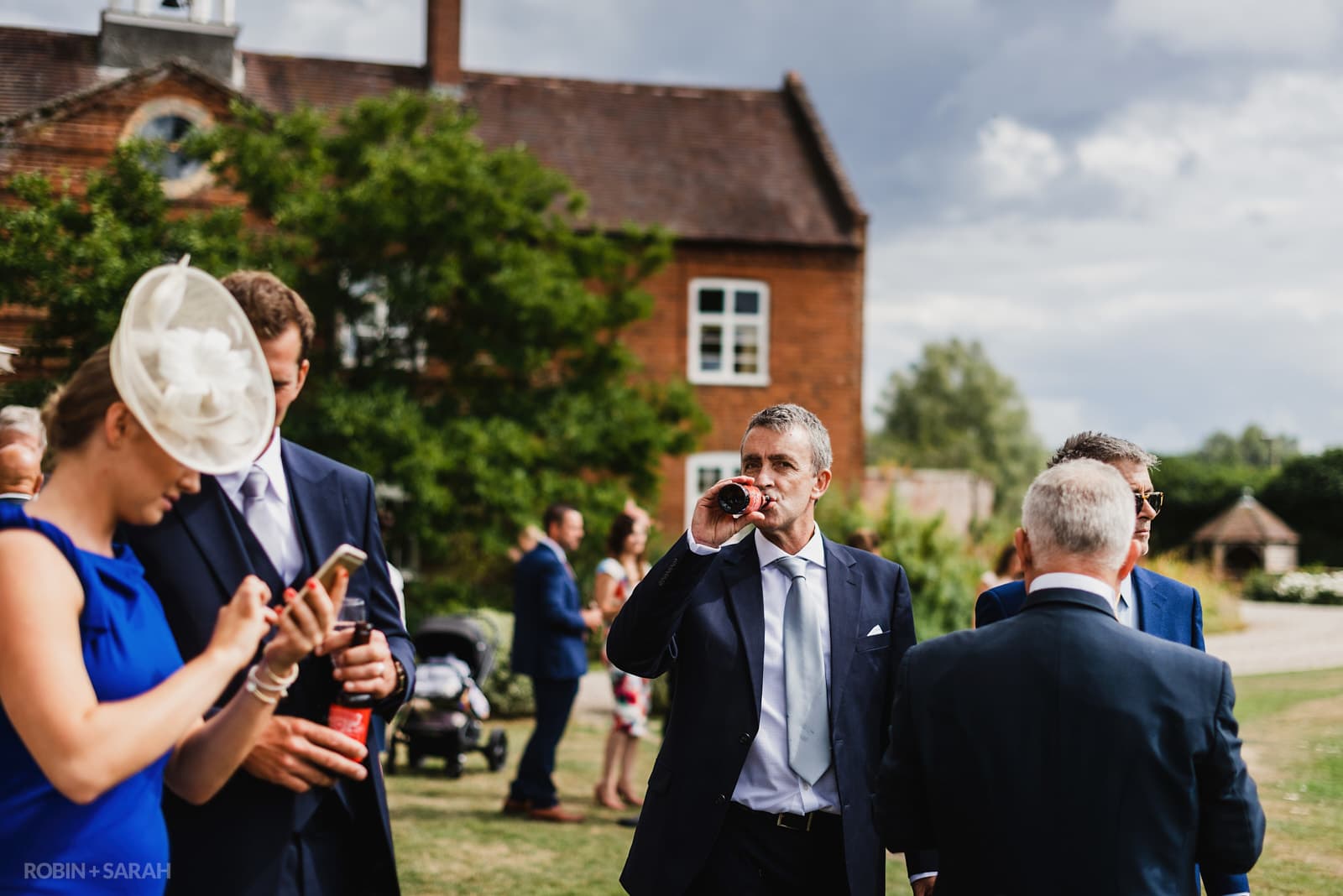 Wedding guests drink and chat during reception at Delbury Hall