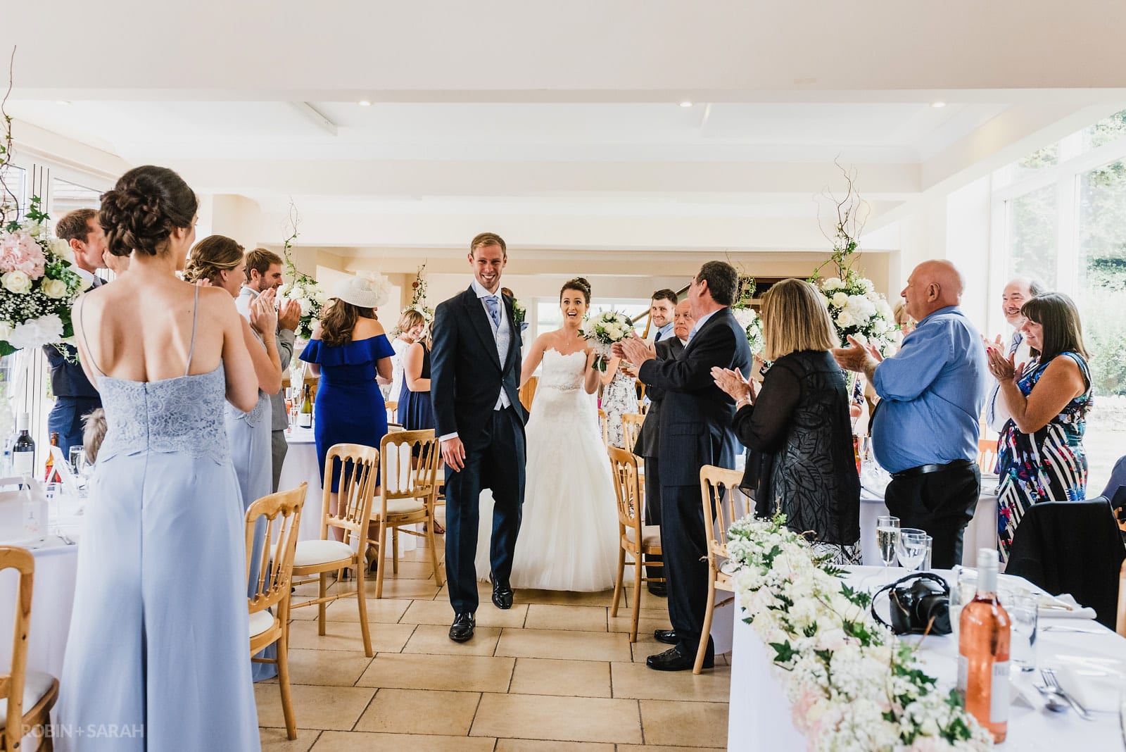 Bride and groom enter Coachhouse at Delbury Hall for meal as guests clap