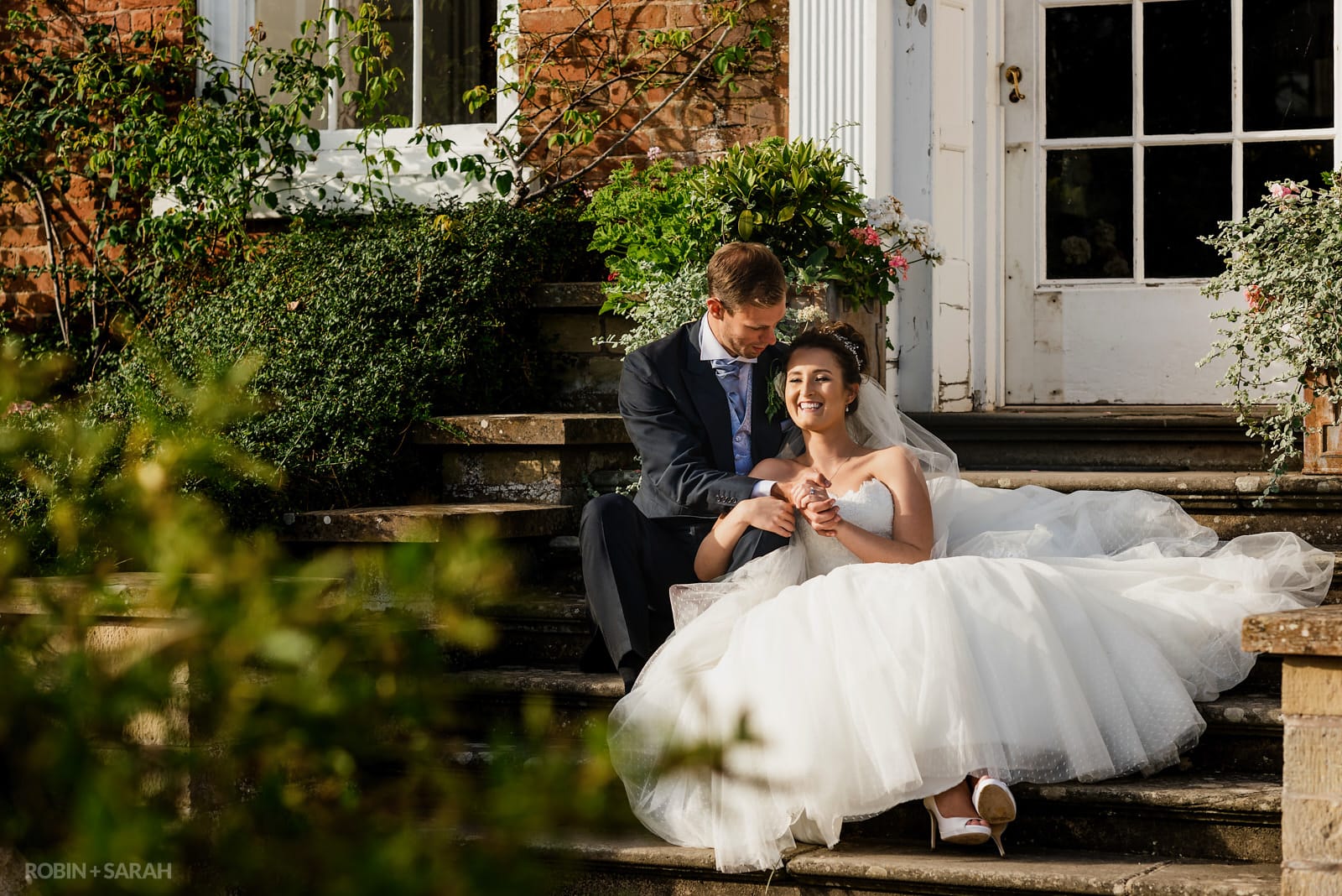 Bride and groom laughing while sitting on steps and enjoying the evening sunshine