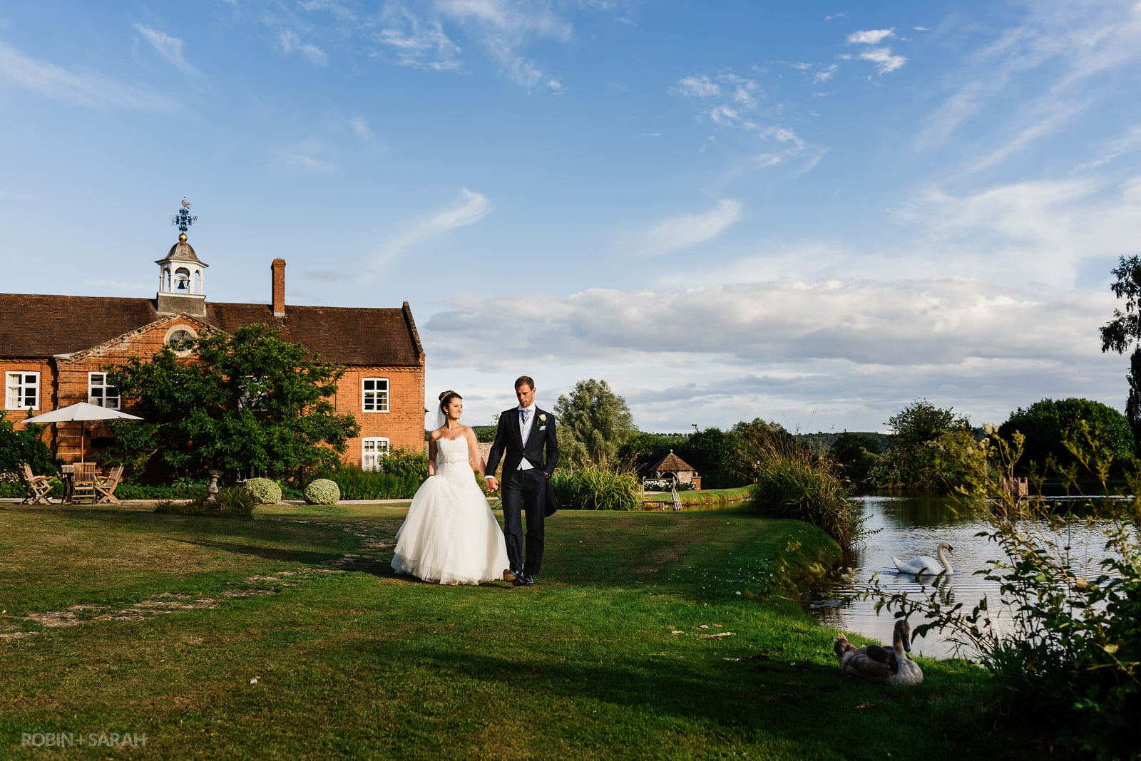 Bride and groom walking next to pond in beautiful gardens at Delbury Hall