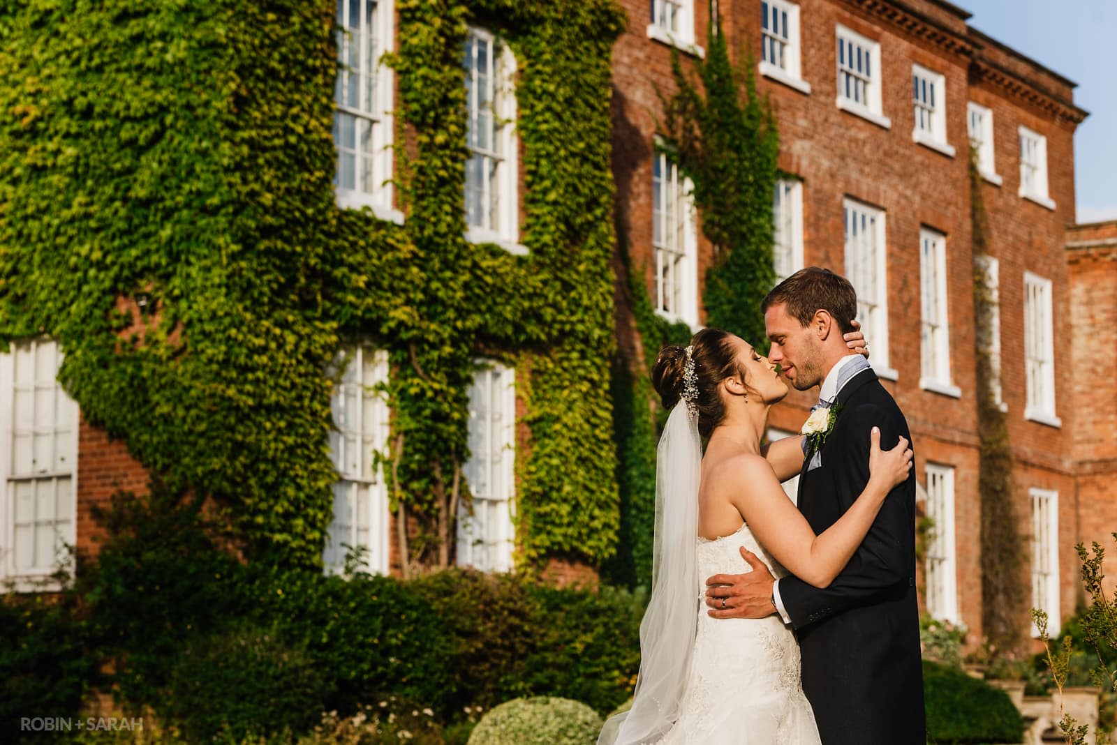 Bride and groom about to kiss in front of Delbury Hall