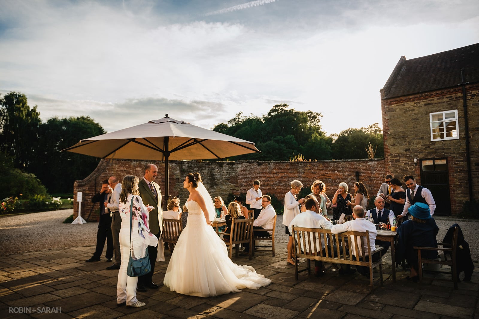 Wedding guests relaxing in the evening sunlight in courtyard at Delbury Hall