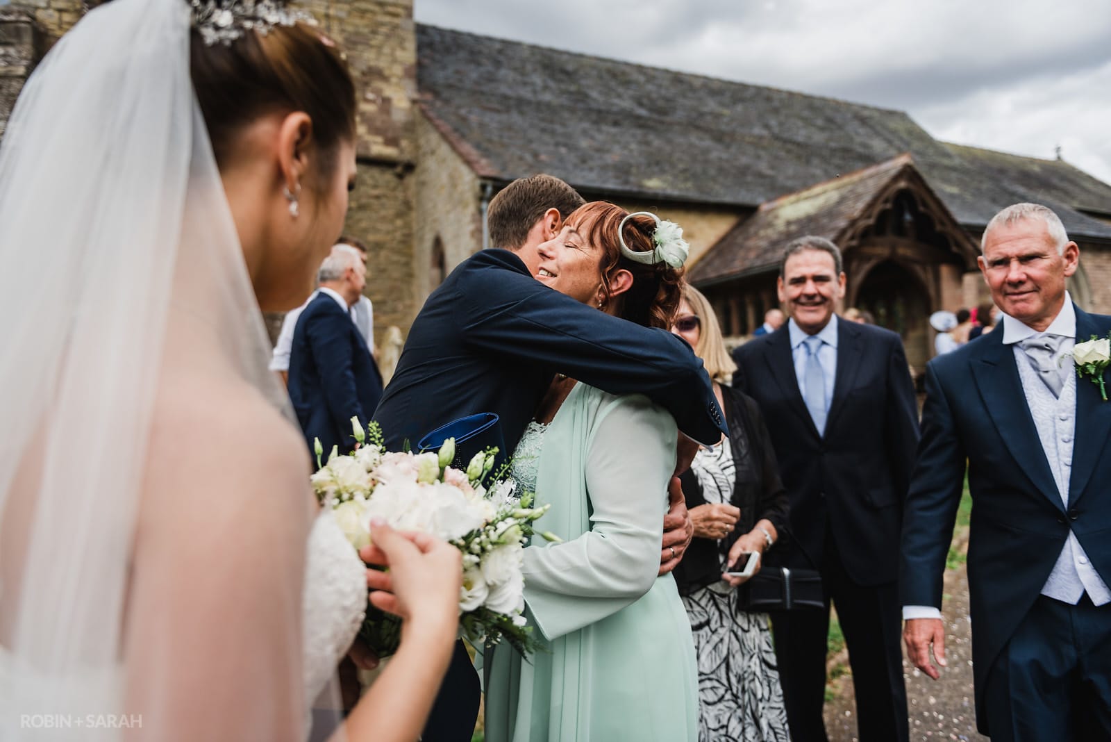 Groom hugs his mum after church wedding ceremony