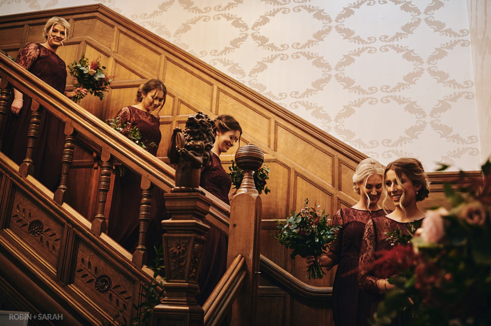 Bridesmaids walk down staircase at Hampton Manor