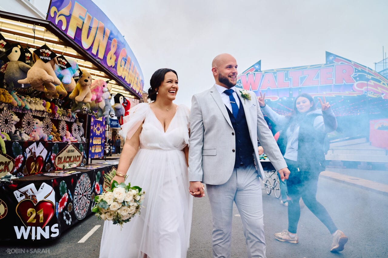 Newly married bride and groom walking through funfair
