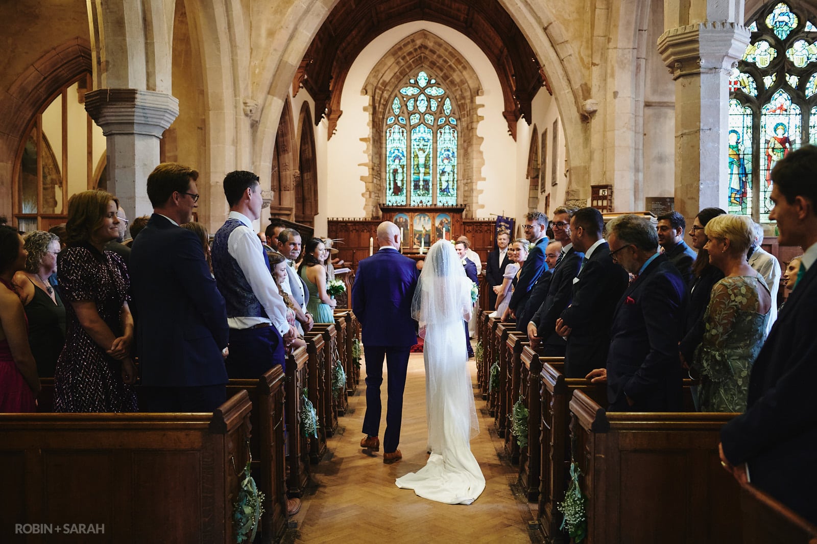 Bride and father enter wedding ceremony at St Peter's church Dunchurch as groom reacts