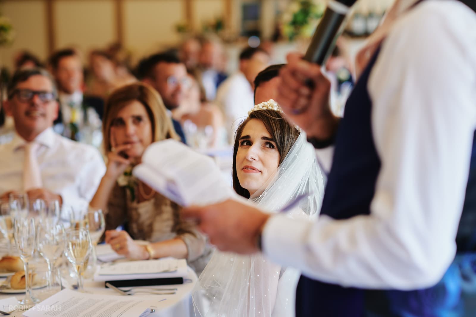Bride listens to groom give speech during wedding meal