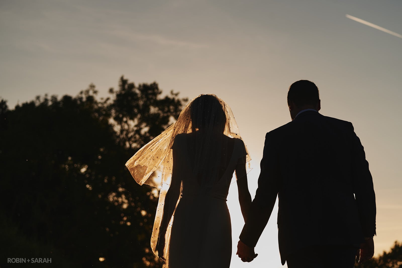 Bride and groom silhouetted against the setting sun