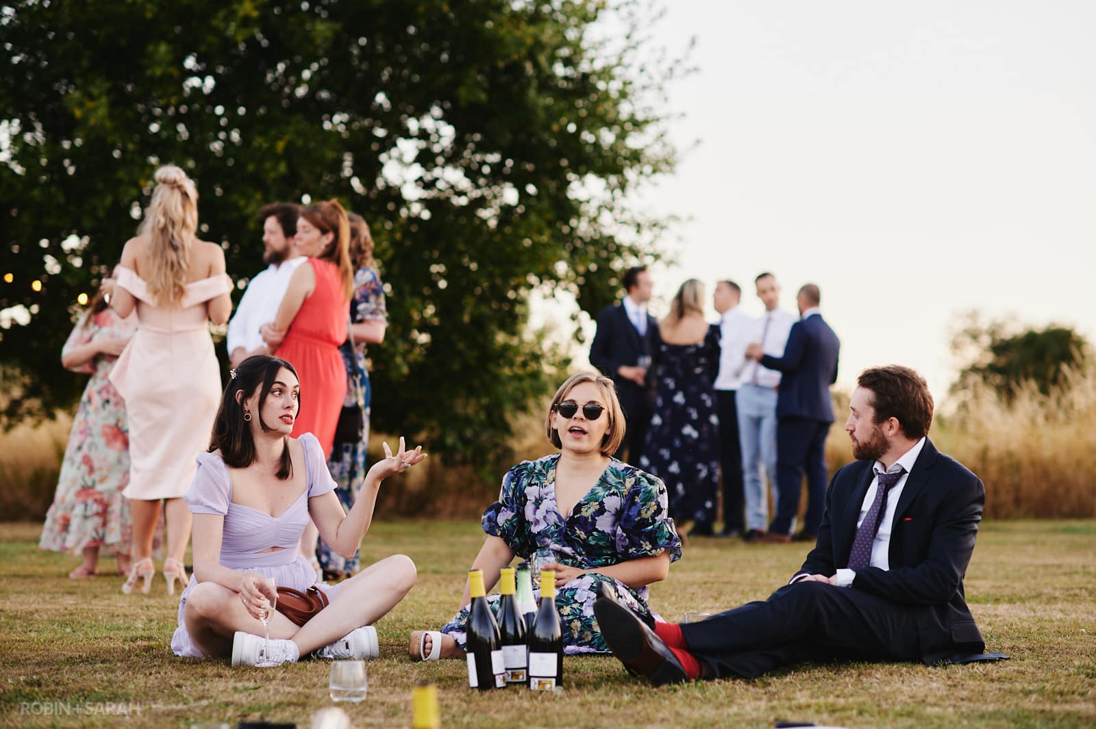 Wedding guests chat and relax outside in evening light