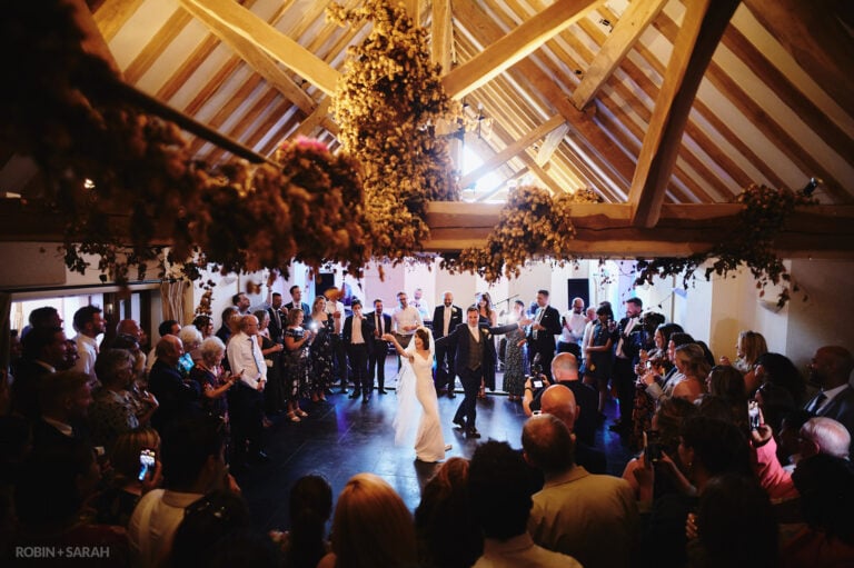 Bride and groom's first dance in barn at Wethele Manor as guests watch