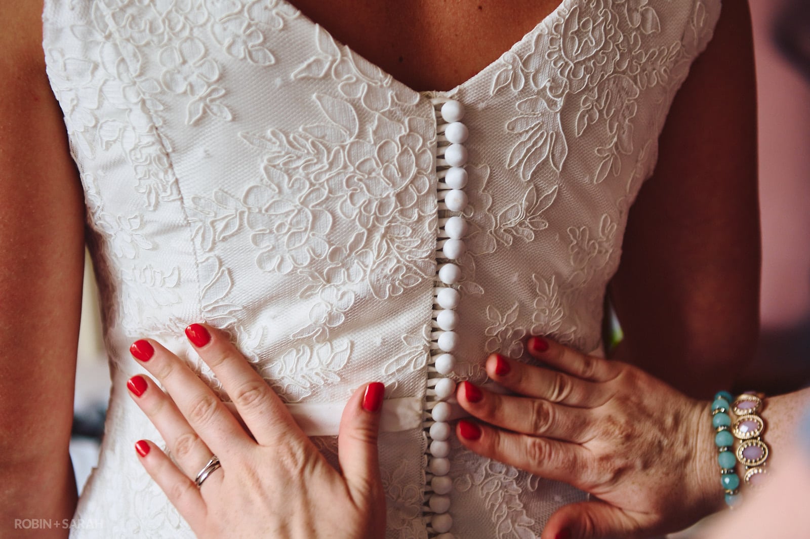 Bridesmaids hands on white wedding dress