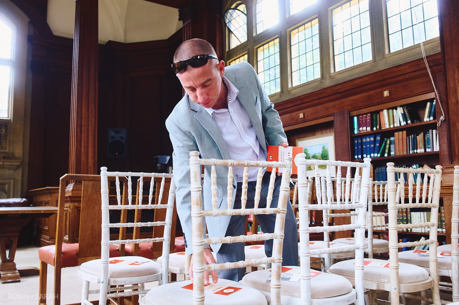 Groomsman places order of service cards on chairs