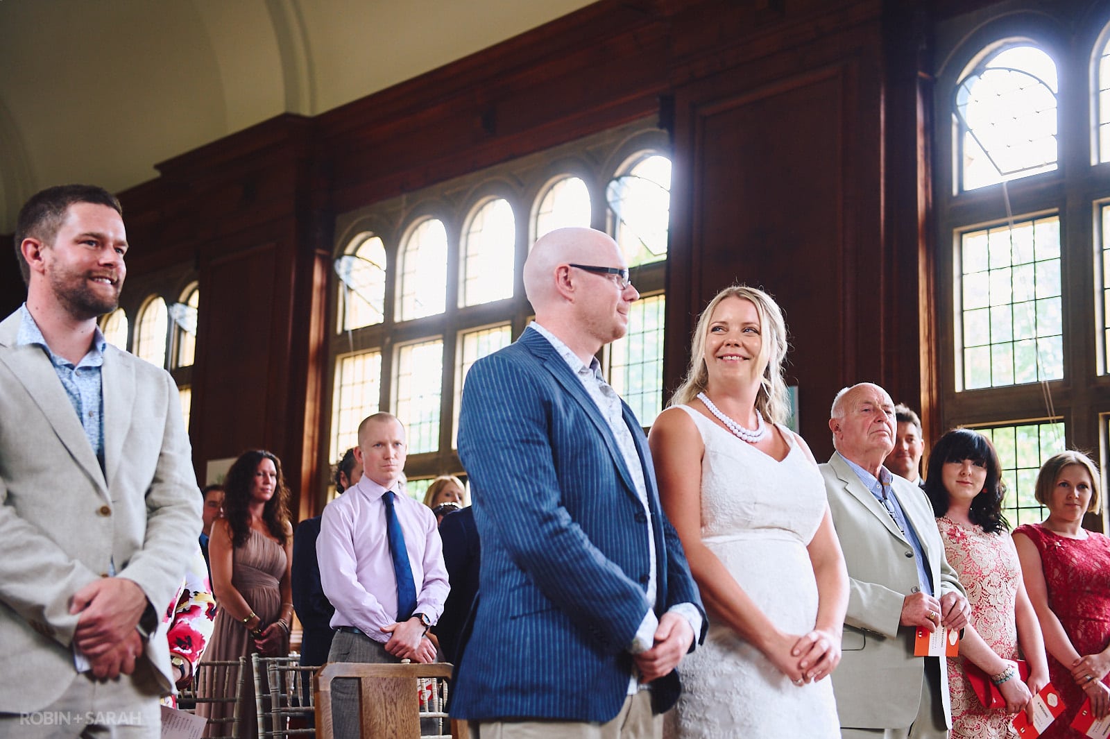 Bride and groom smile at each other during wedding ceremony in Malvern College Memorial Library