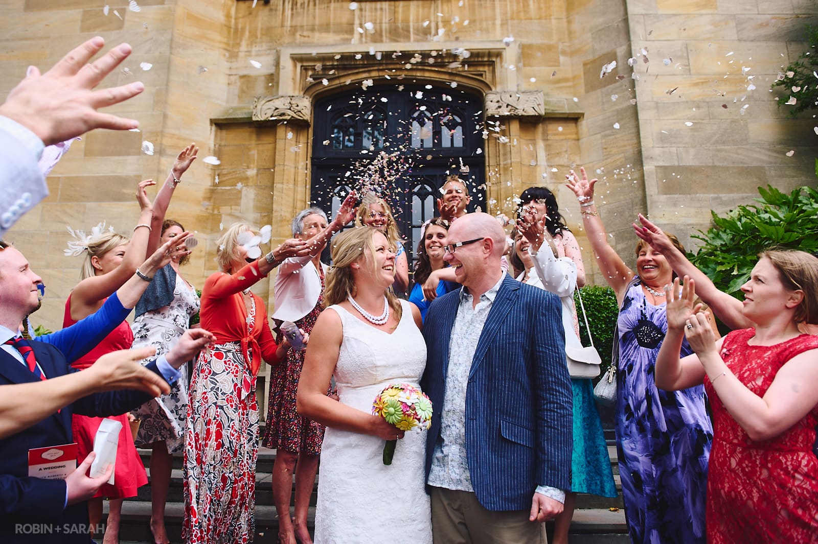 Bride and groom have confetti thrown over them by guests outside Malvern College Memorial Library