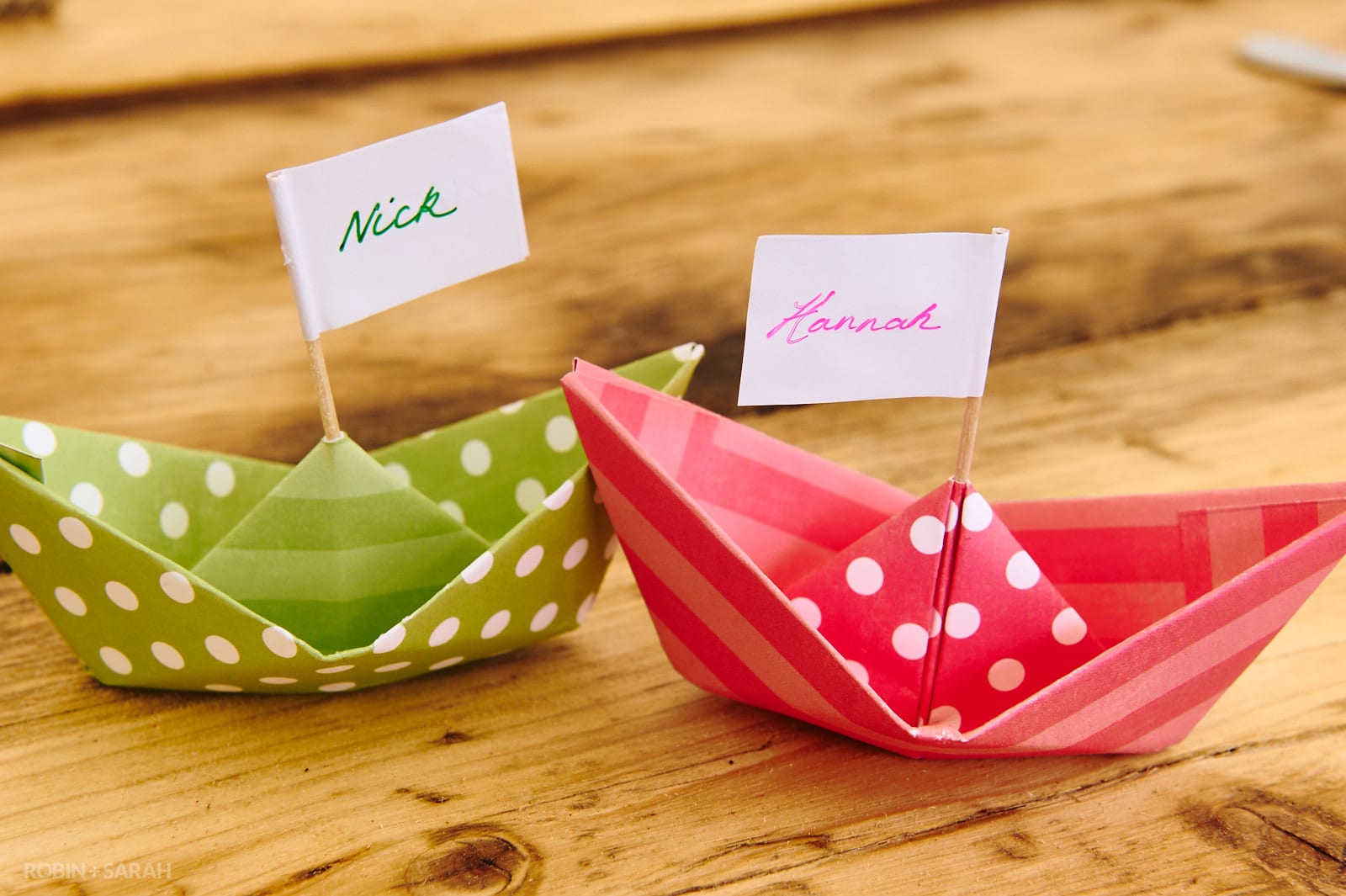 Paper boats with names written on a paper flag