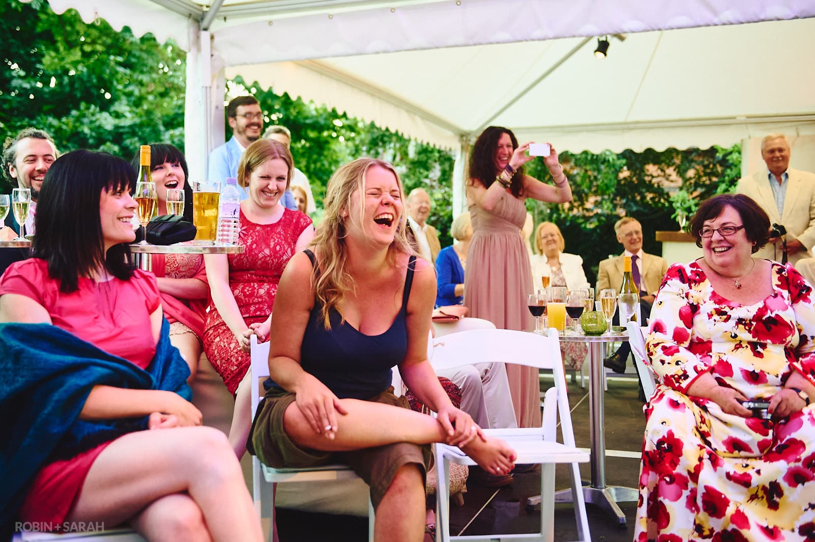 Bride and guests laughing during speeches at home wedding
