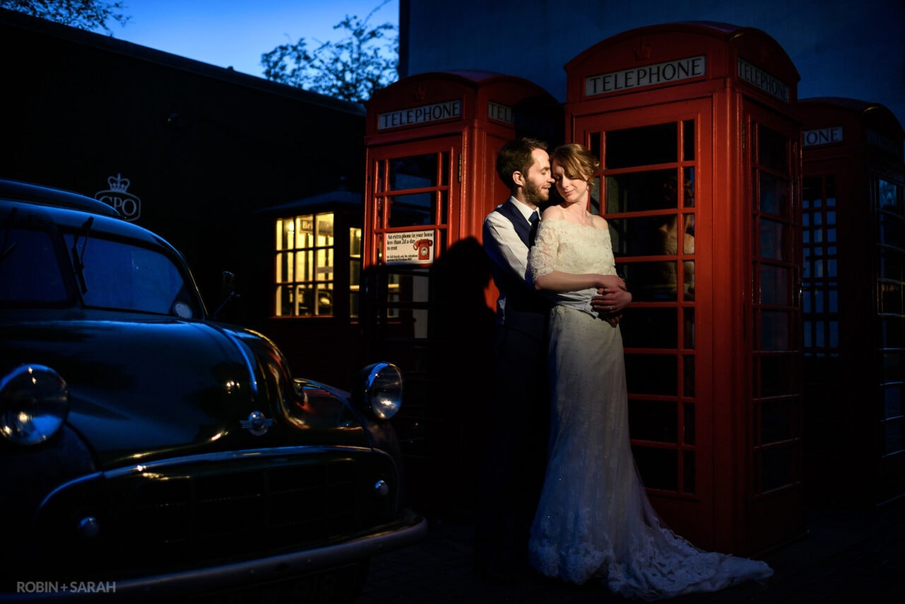 Bride and groom next to old telephone boxes at night