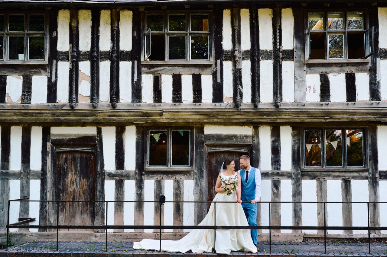 Bride and groom relaxing in front of old half-timber building at Avoncroft Museum on their wedding day
