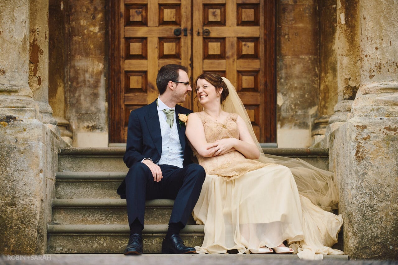 Bride and groom laughing together on steps at Elmore Court