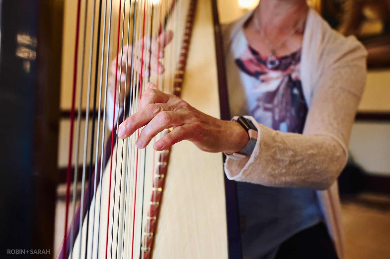 Detail of harpists hands as she plays during wedding ceremony