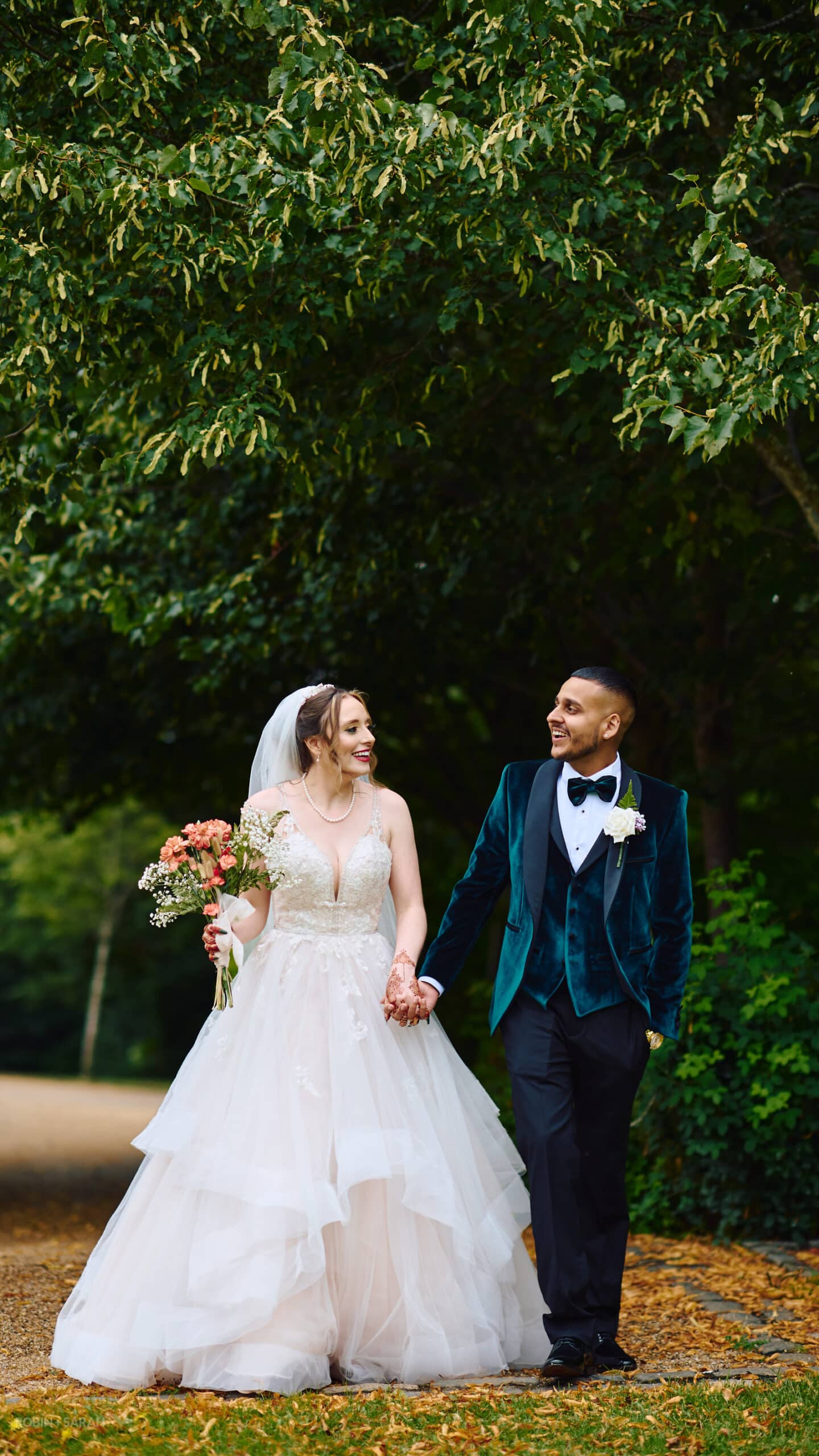 Bride and groom walk through beautiful gardens at Spring Grove House