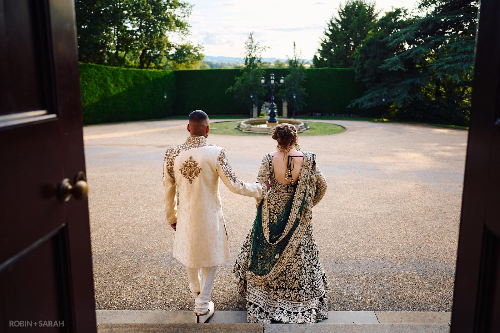 Bride and groom in Indian wedding outfits walk at Spring Grove House