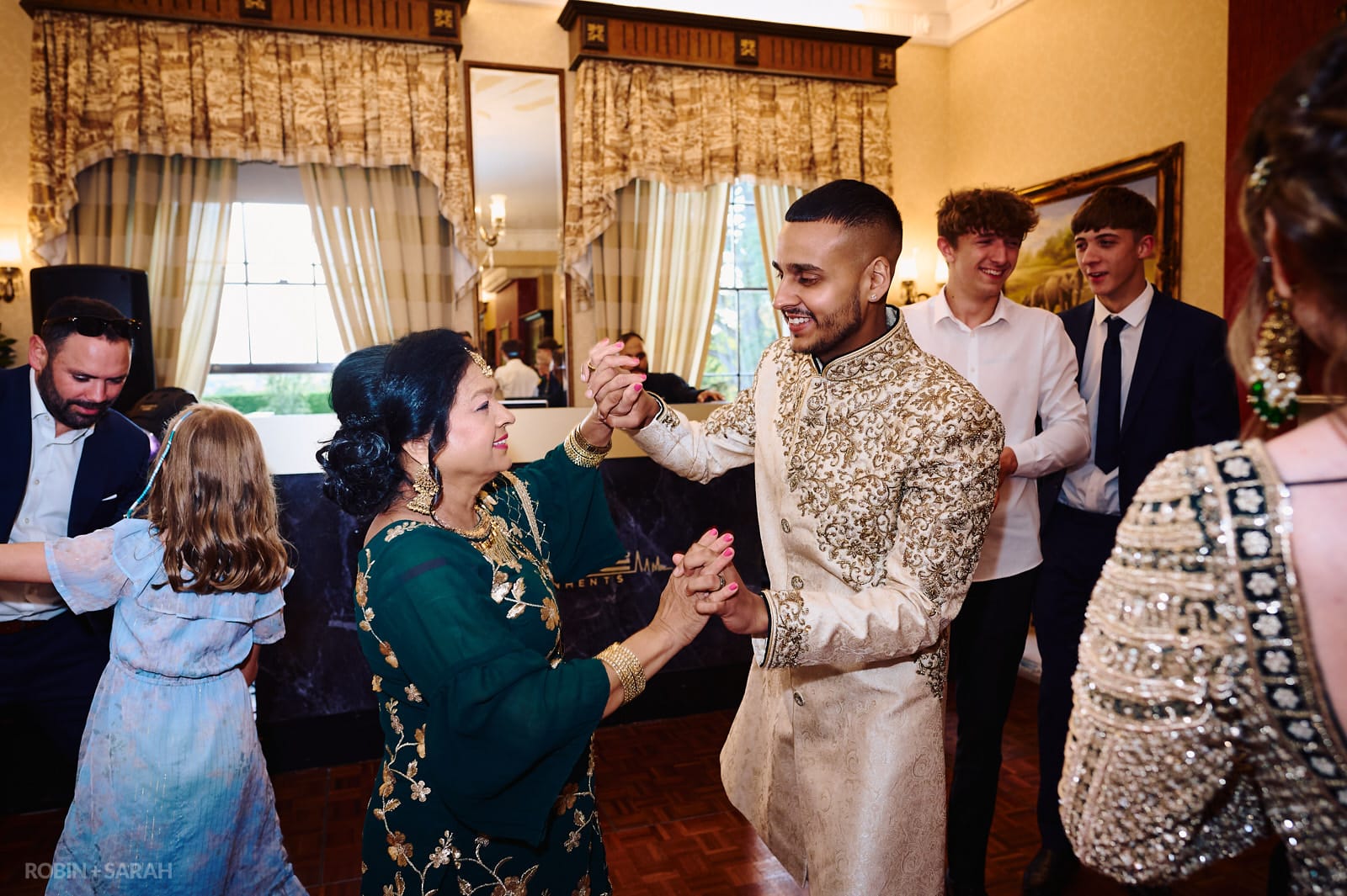 Bride, groom and guests dancing at fusion wedding held at Spring Grove House