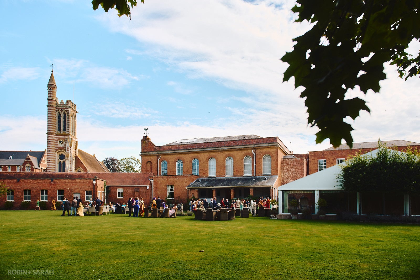 View across lawn of St Anne's Hall at Stanbrook Abbey, with wedding guests relaxing with drinks