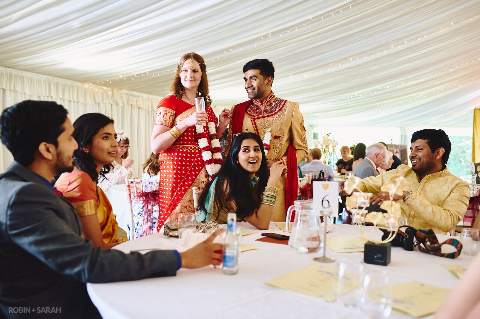 Bride and groom chat with wedding guests during meal