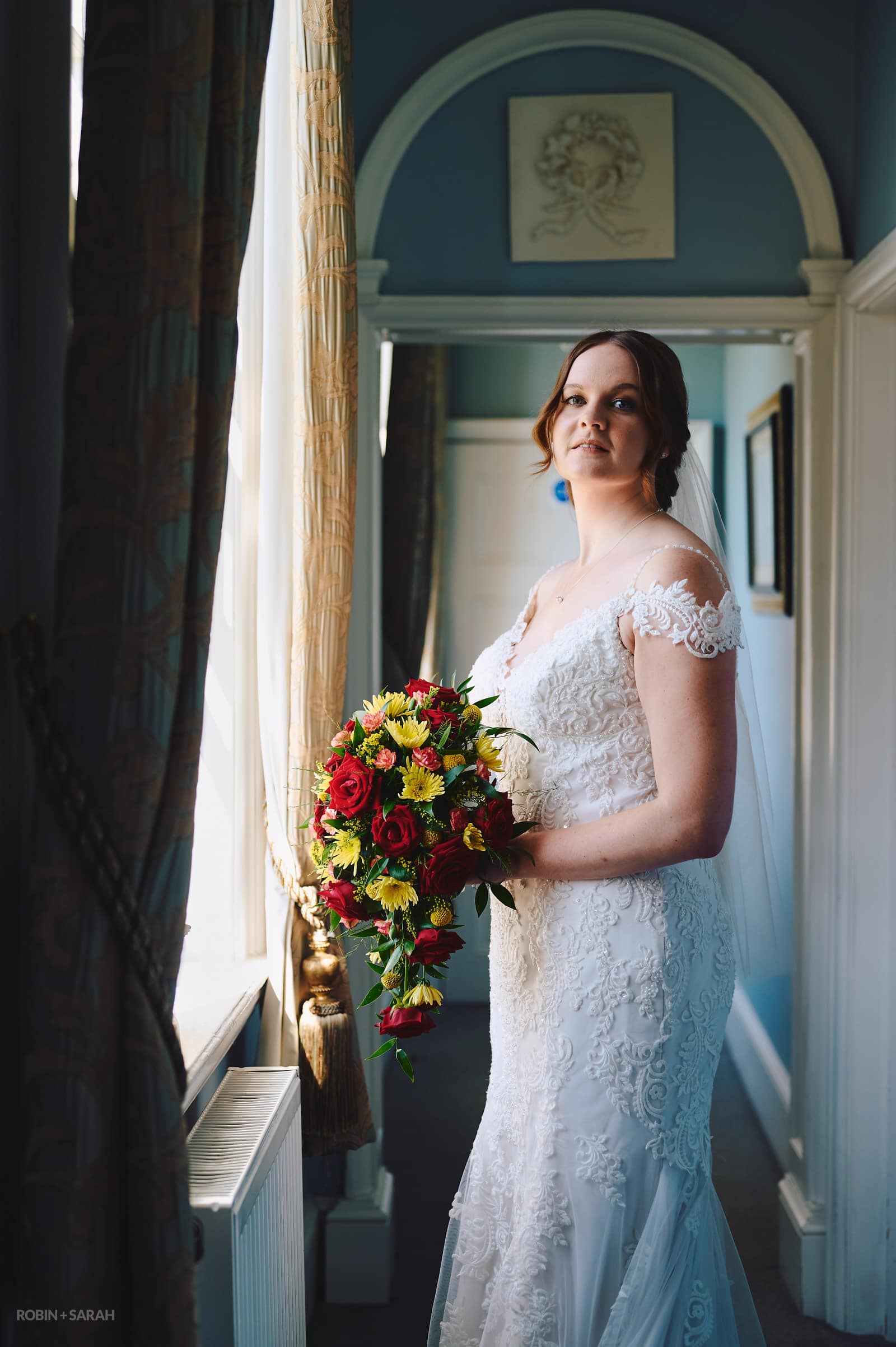 Portrait of bride in white wedding dress in hallway at Stanbrook Abbey