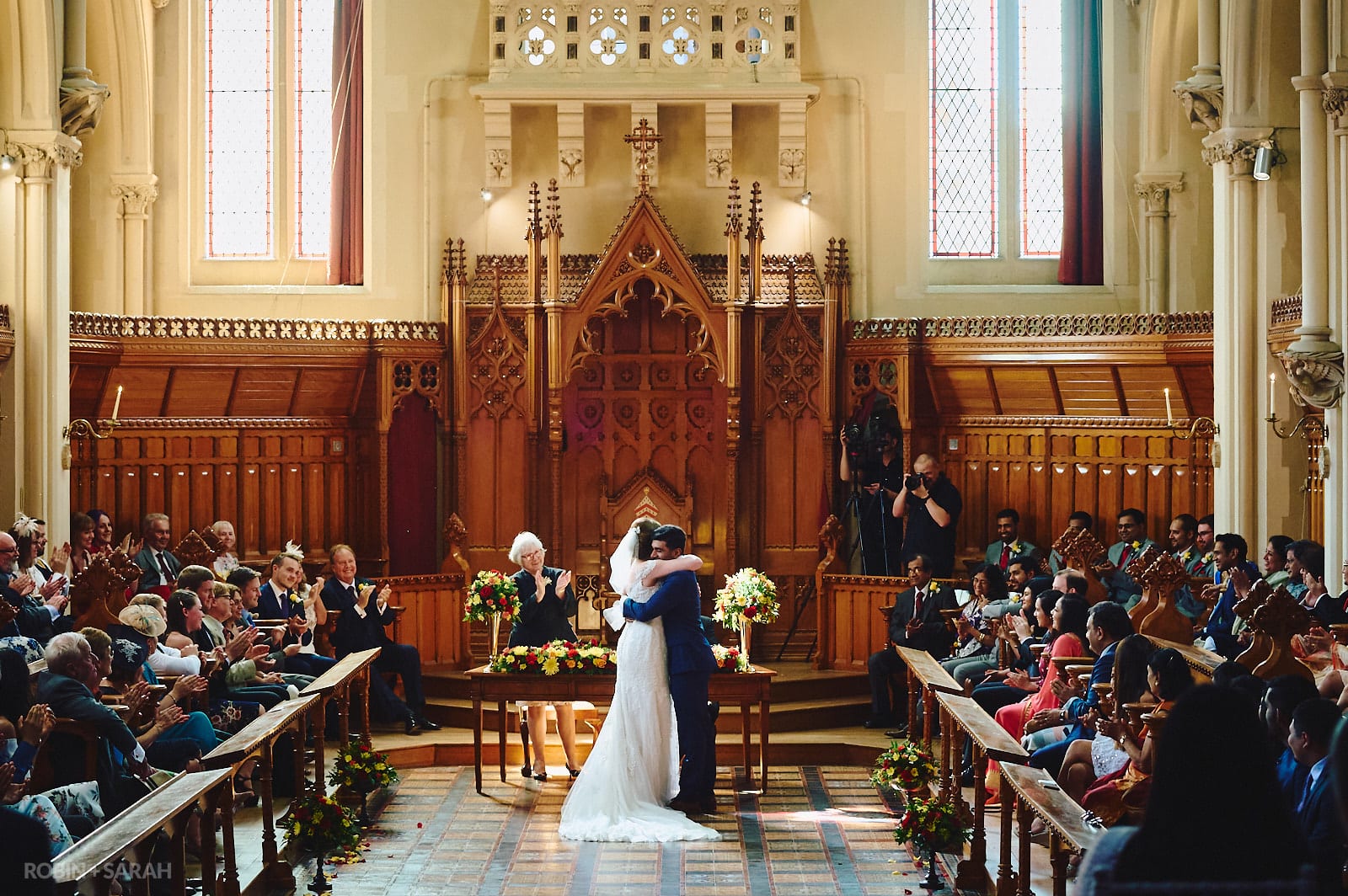 Bride and groom hug at end of wedding ceremony in Callow Great Hall at Stanbrook Abbey