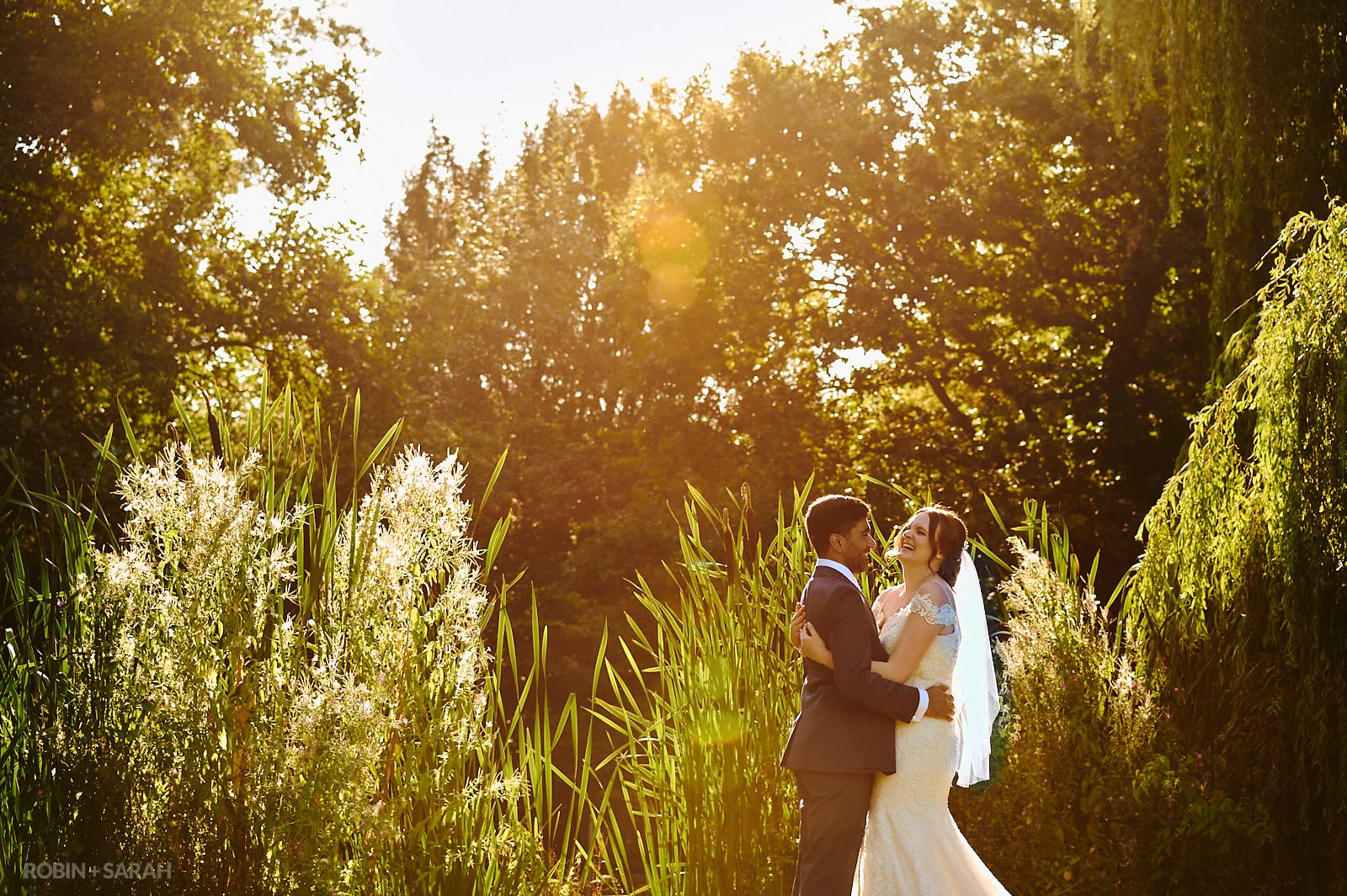 Bride and groom laughing together in gardens at Stanbrook Abbey